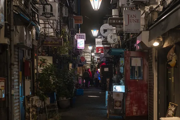 Narrow alley of Shinjuku Golden Gai at night lined with small bars and neon signs
