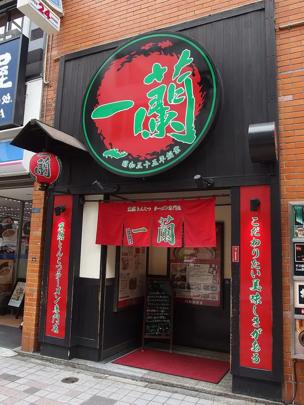 Storefront of Ichiran ramen restaurant in Shinjuku with large red circular logo and red noren curtains