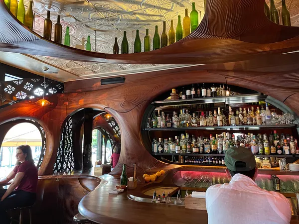 Interior of Bar Raval Toronto showing the iconic curved mahogany bar with sculpted wood panels and tin ceiling