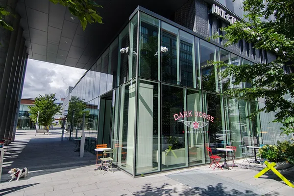 Exterior of Dark Horse Espresso Bar with large branded signage on glass facade, outdoor cafe tables