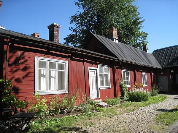 Historic red wooden Qwensel House courtyard in Turku, home of Cafe Qwensel, with cobblestone path and summer garden