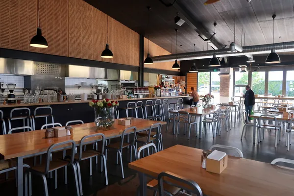 Prefab cafe interior in Wellington showing communal tables, pendant lights and open kitchen