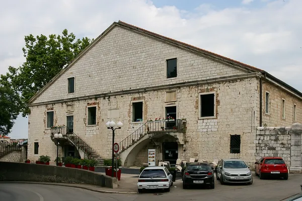 Exterior of the historic Venetian Arsenal building in Zadar, a large stone structure with a double staircase and outdoor seating